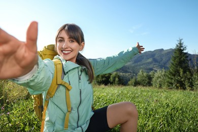 Photo of Smiling woman with backpack taking selfie in beautiful mountains