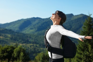 Young woman in sunglasses with backpack in beautiful mountains