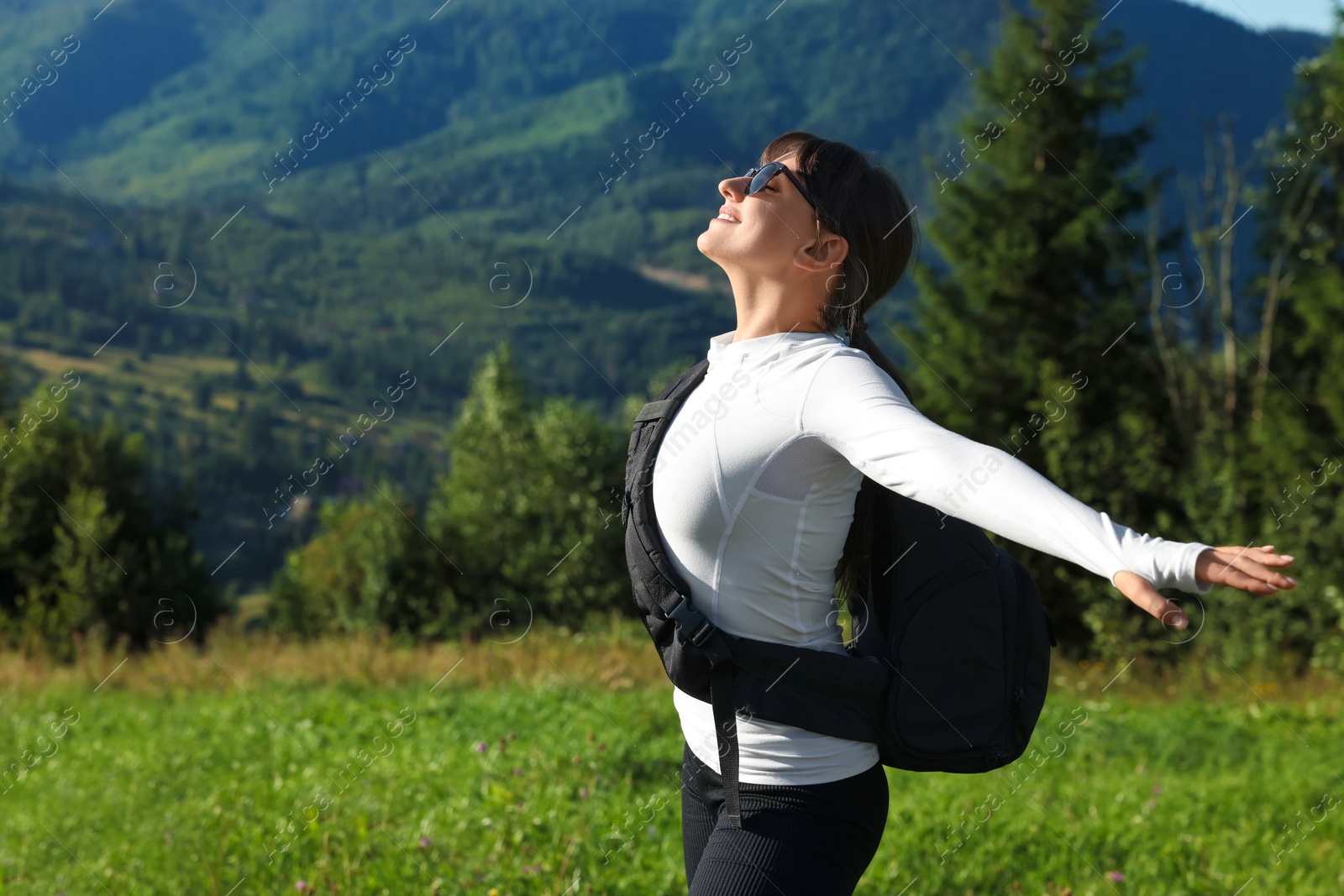 Photo of Young woman in sunglasses with backpack in beautiful mountains