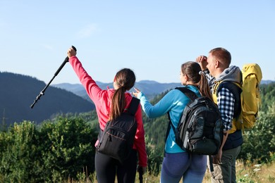 Friends with backpacks in beautiful mountains, back view