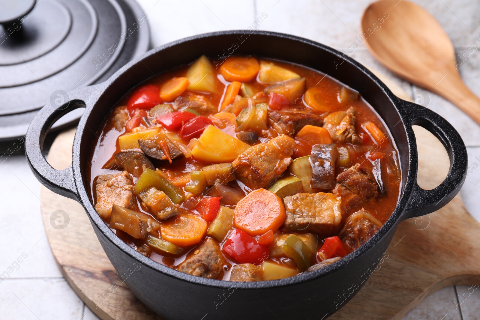 Photo of Delicious stew with vegetables in pot on light textured table, closeup