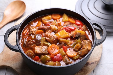 Photo of Delicious stew with vegetables in pot on light textured table, closeup