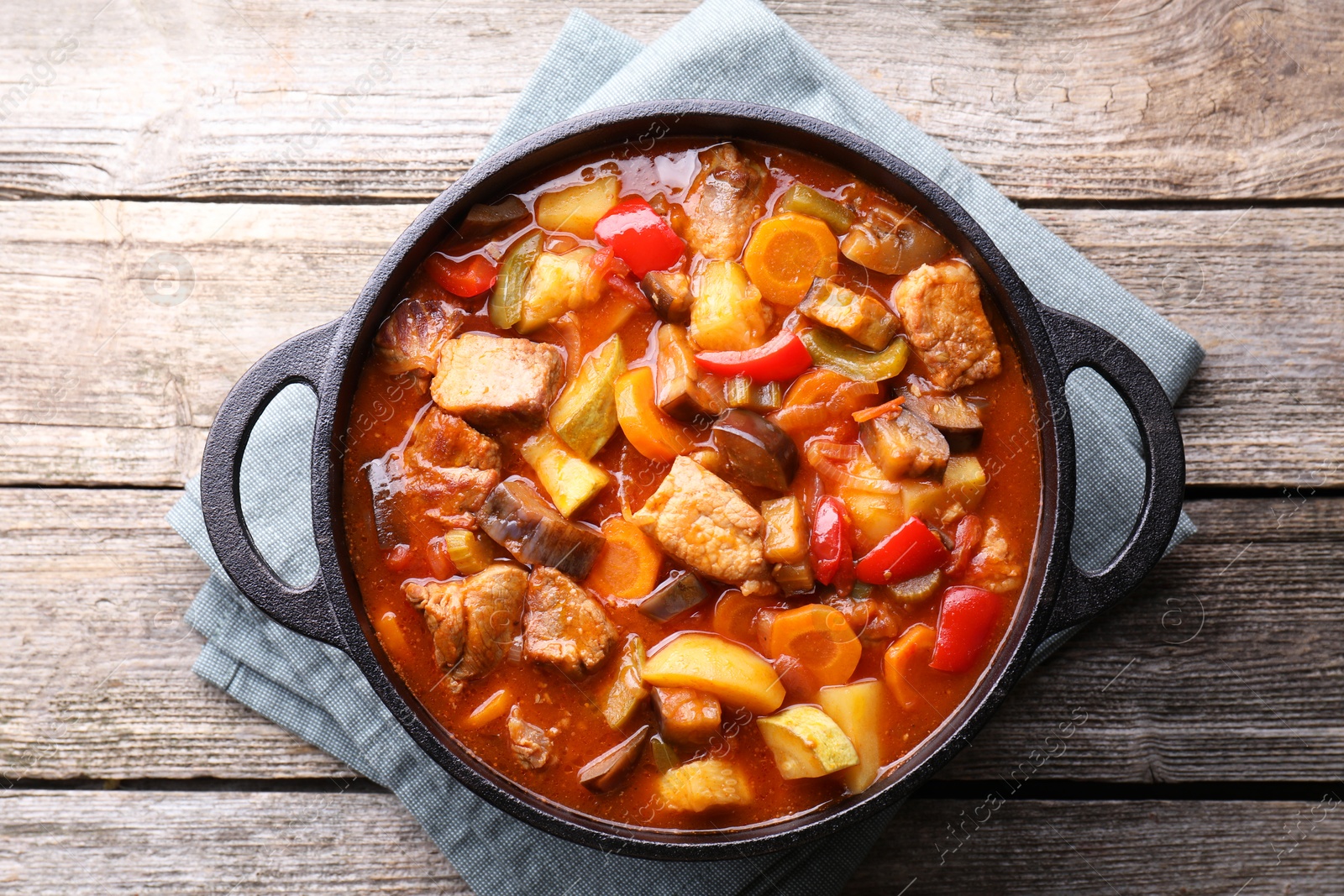 Photo of Delicious stew with vegetables in pot on wooden table, top view