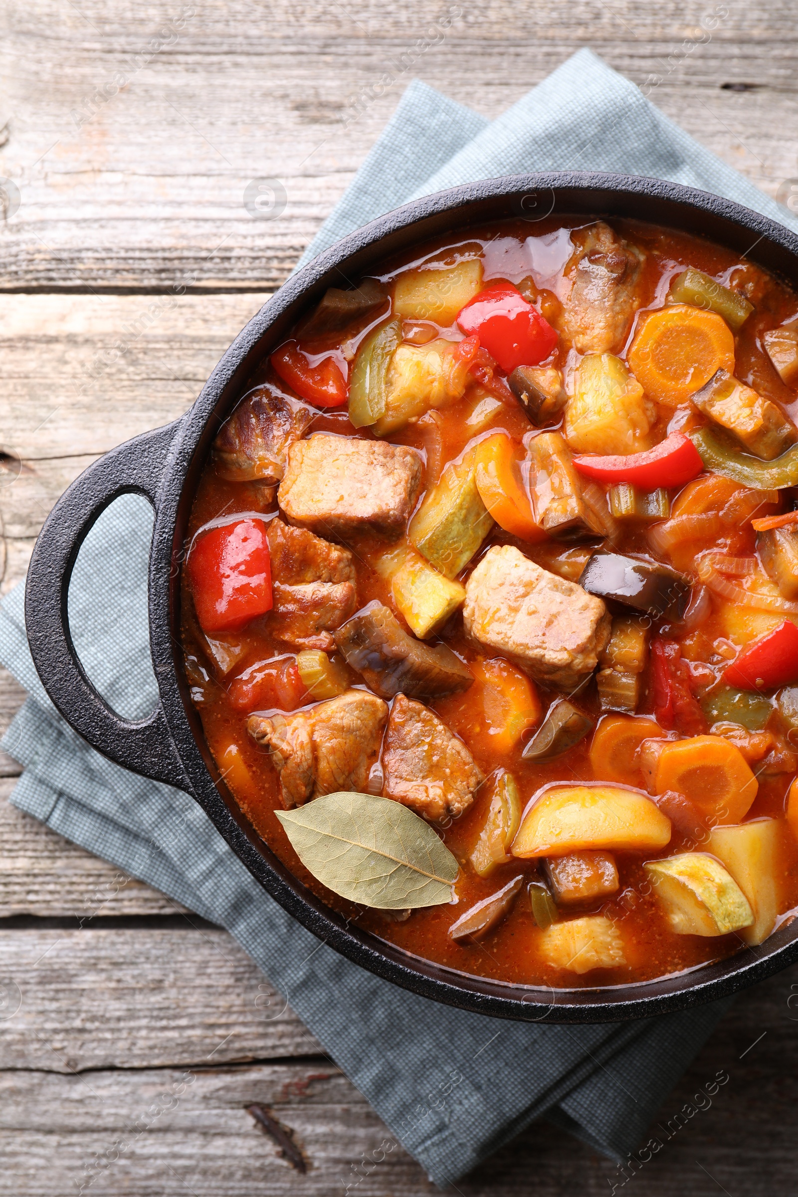 Photo of Delicious stew with vegetables in pot on wooden table, top view