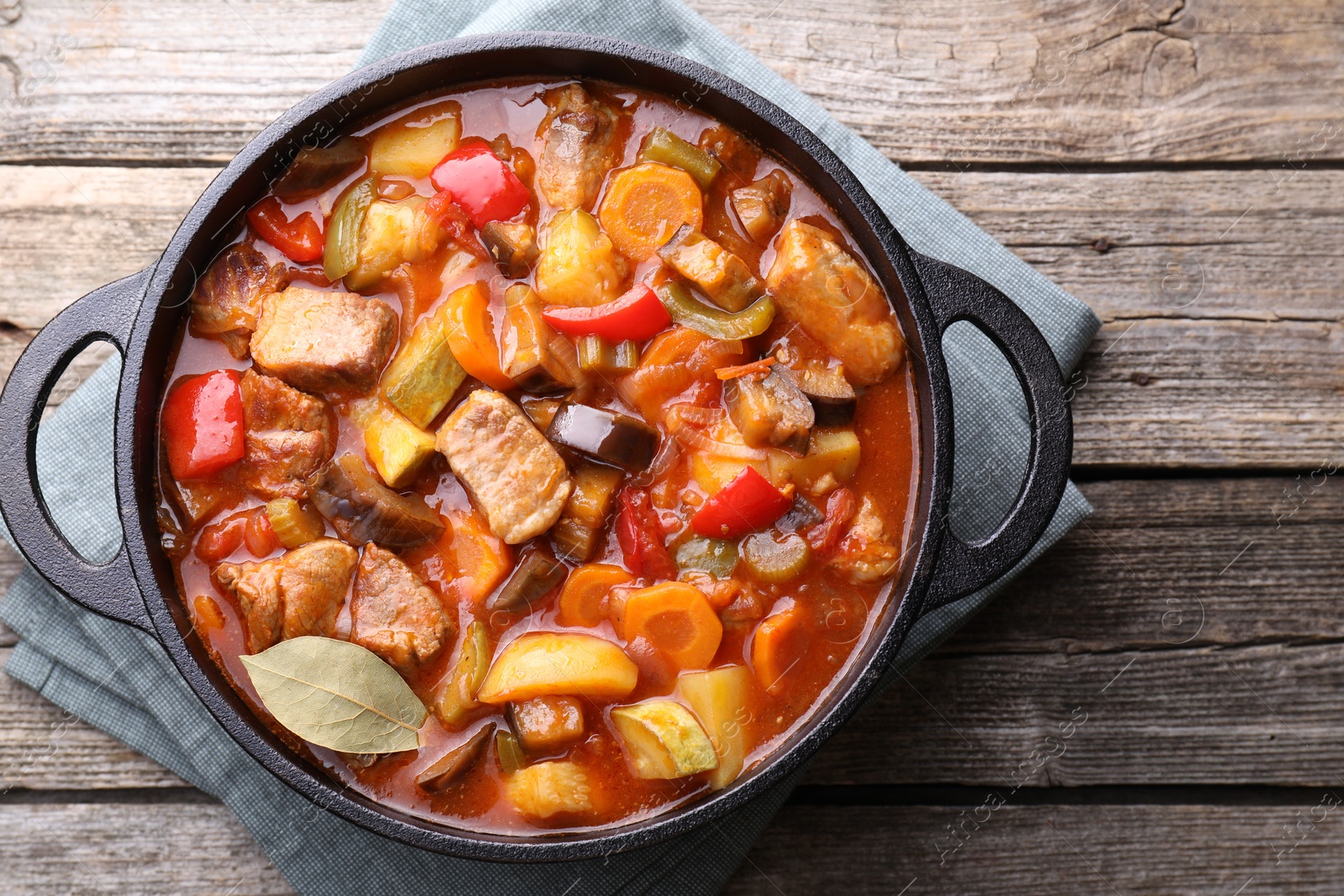 Photo of Delicious stew with vegetables in pot on wooden table, top view