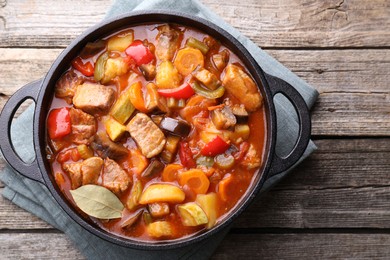 Delicious stew with vegetables in pot on wooden table, top view