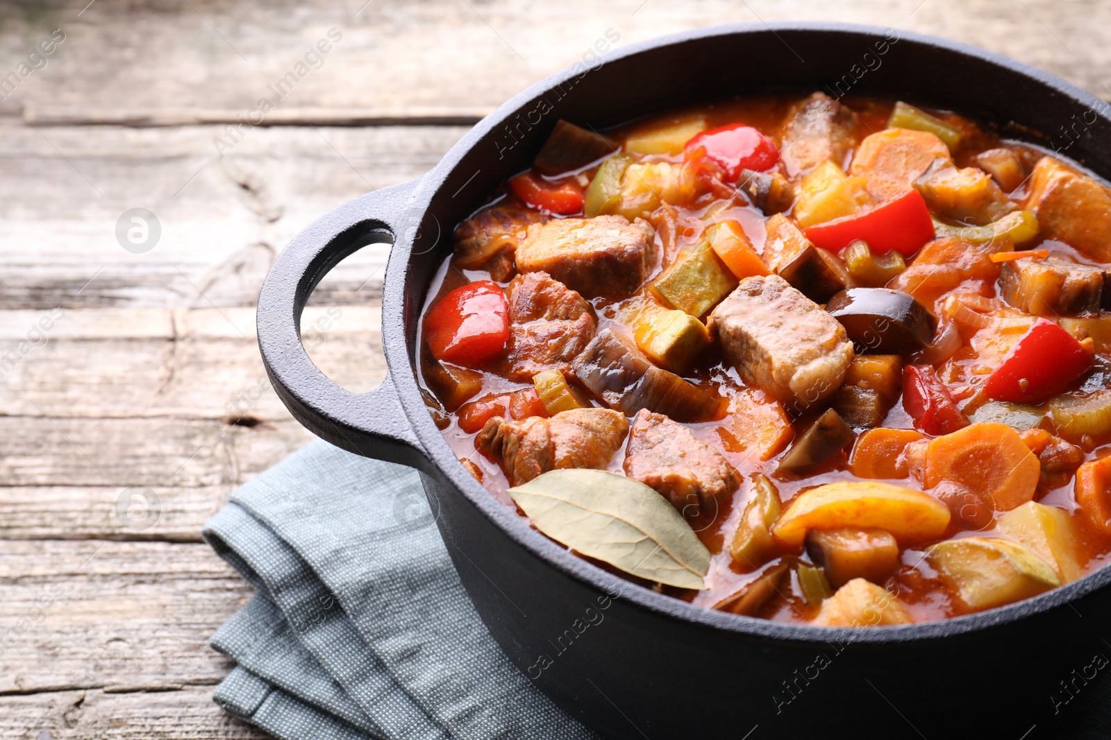 Photo of Delicious stew with vegetables in pot on wooden table, closeup