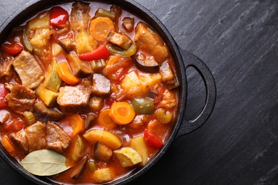 Photo of Delicious stew with vegetables in pot on gray textured table, top view