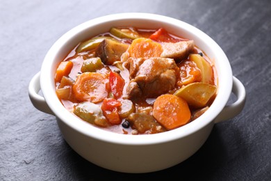 Photo of Delicious stew with vegetables in bowl on gray textured table, closeup