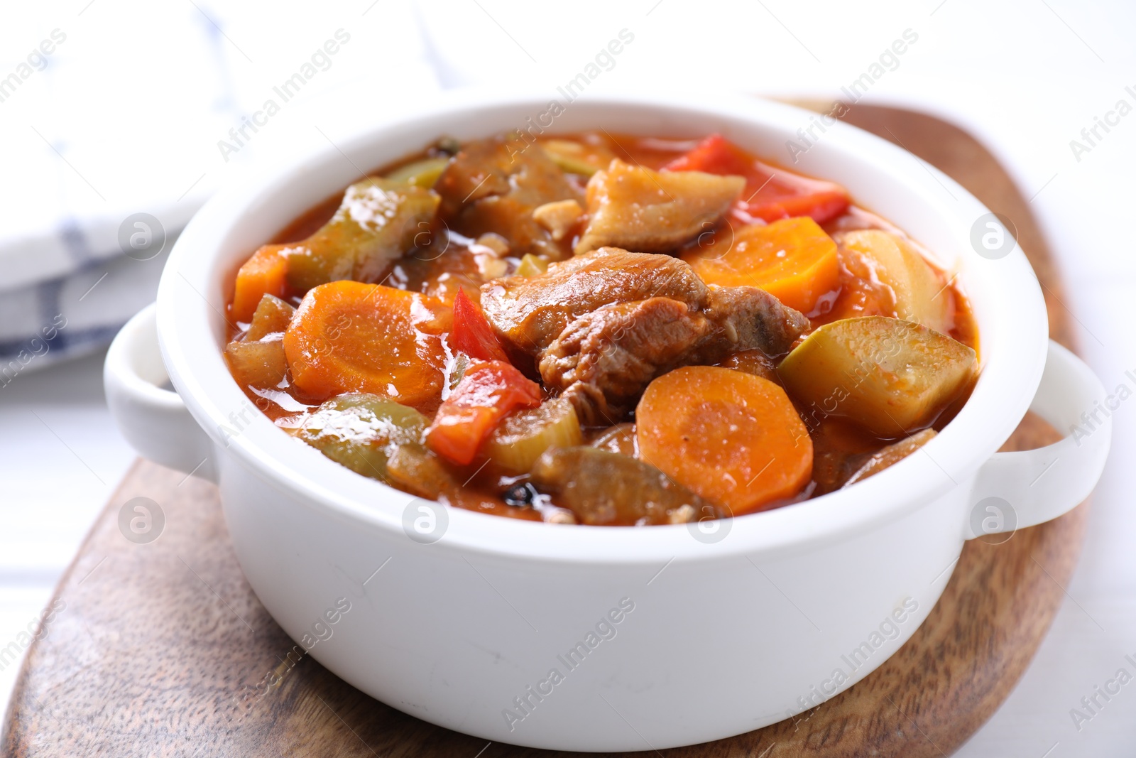 Photo of Delicious stew with vegetables in bowl on white table, closeup