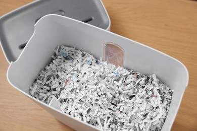 Photo of Shredder and basket with paper strips on wooden table, above view