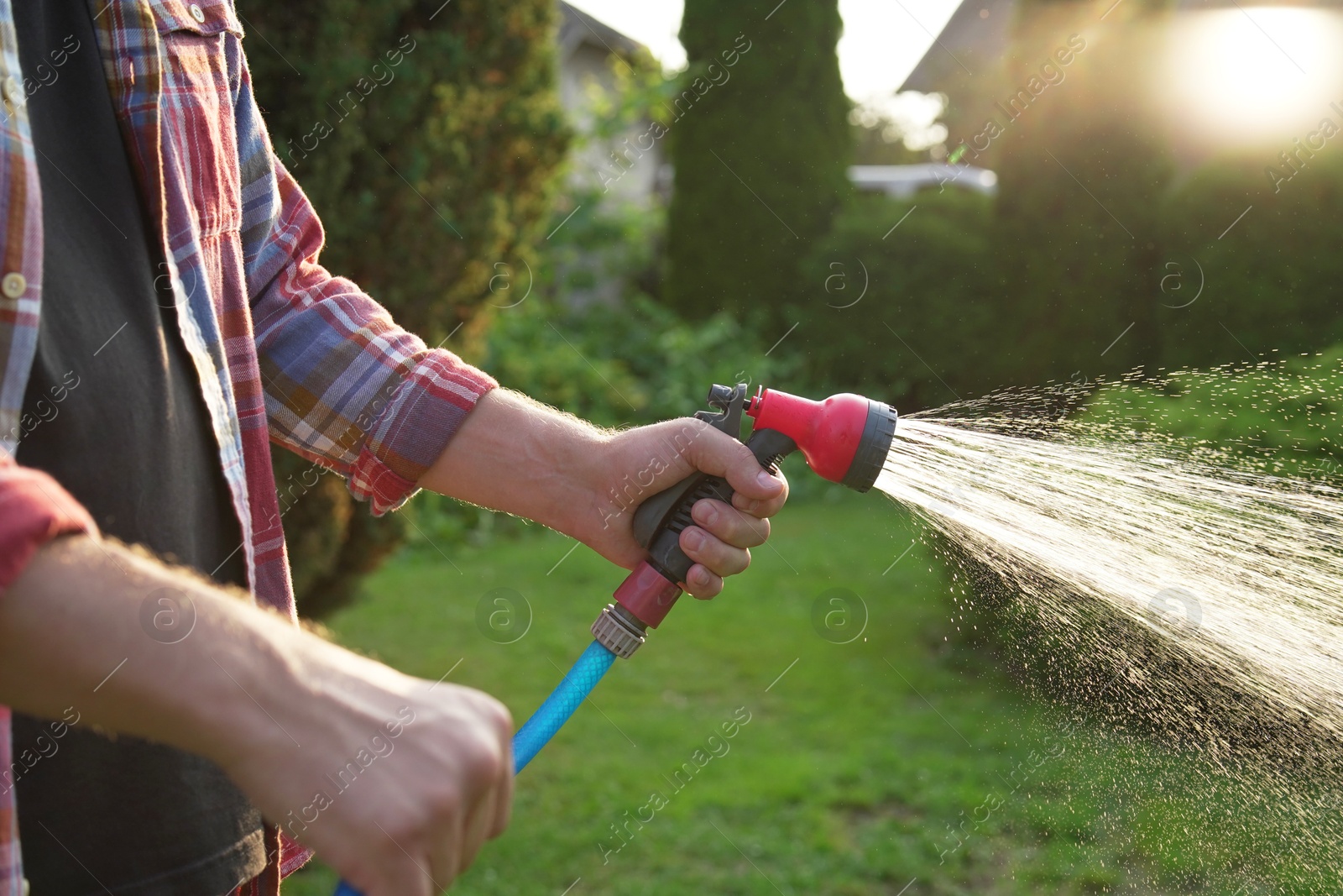 Photo of Man watering lawn with hose in backyard, closeup