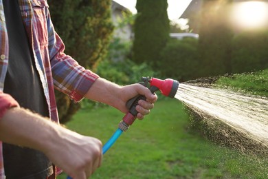 Man watering lawn with hose in backyard, closeup