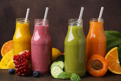 Glass bottles of tasty smoothies and different products on wooden table