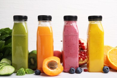 Glass bottles of tasty smoothies and different products on white tiled table