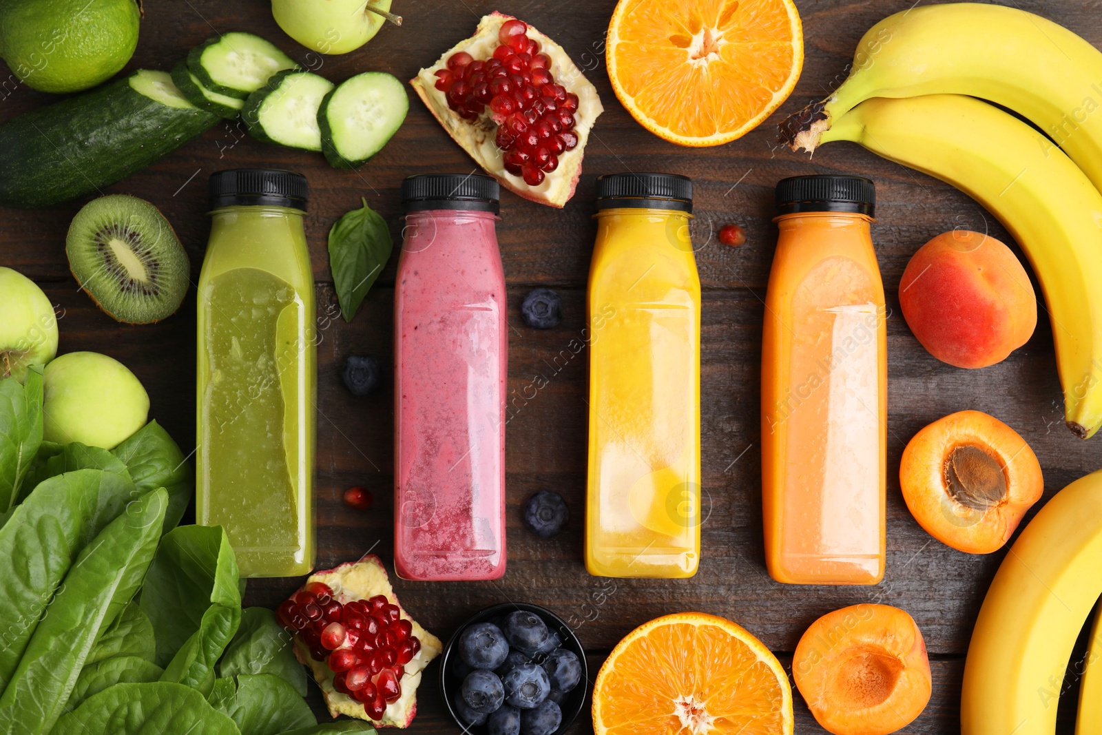 Photo of Glass bottles of tasty smoothies and different products on wooden table, flat lay