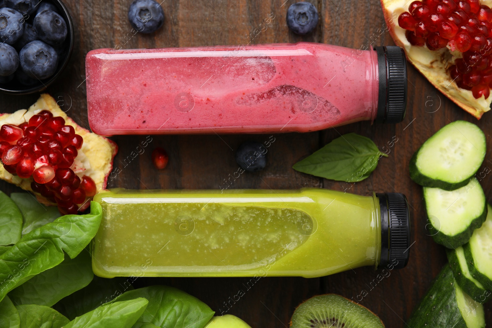 Photo of Glass bottles of tasty smoothies and different products on wooden table, flat lay