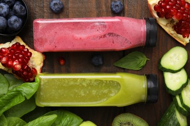 Photo of Glass bottles of tasty smoothies and different products on wooden table, flat lay