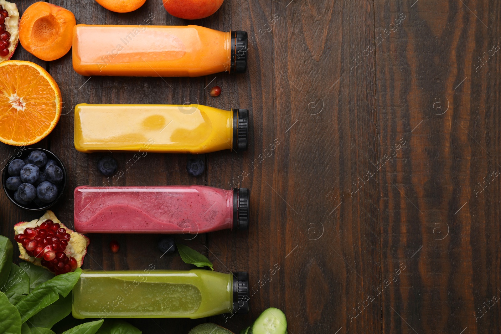 Photo of Glass bottles of tasty smoothies and different products on wooden table, flat lay. Space for text