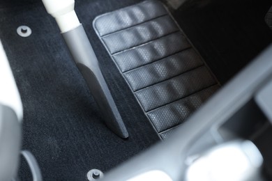 Photo of Cleaning car floor mat with vacuum cleaner, closeup