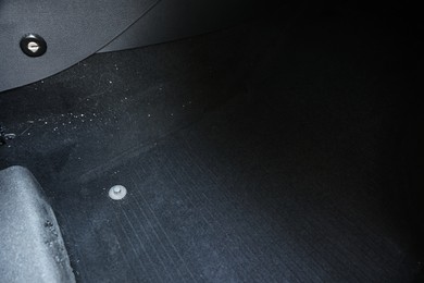 Photo of Black soft car floor mat in auto, closeup