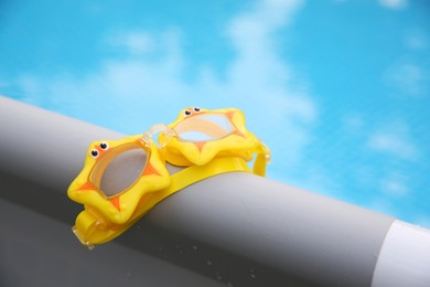 Photo of Cute swimming goggles for kids on top rail of pool, closeup