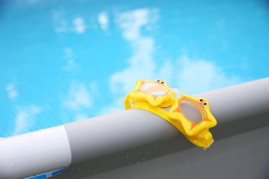 Cute swimming goggles for kids on top rail of pool, closeup