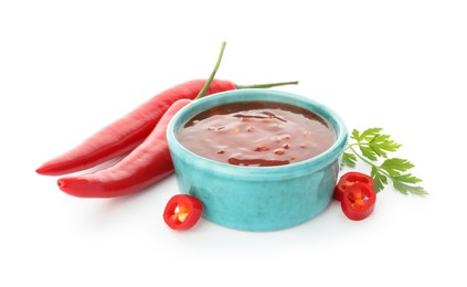 Photo of Hot chili sauce in bowl, parsley and peppers isolated on white