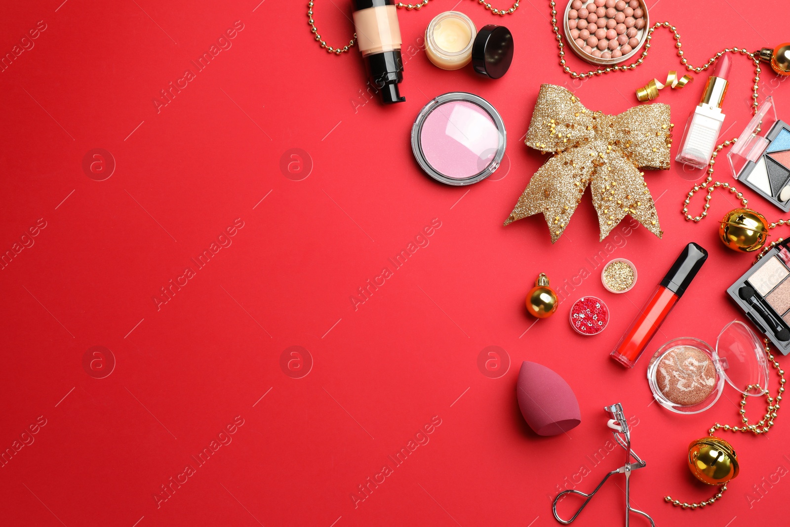 Photo of Flat lay composition with makeup products and Christmas decor on red background. Space for text