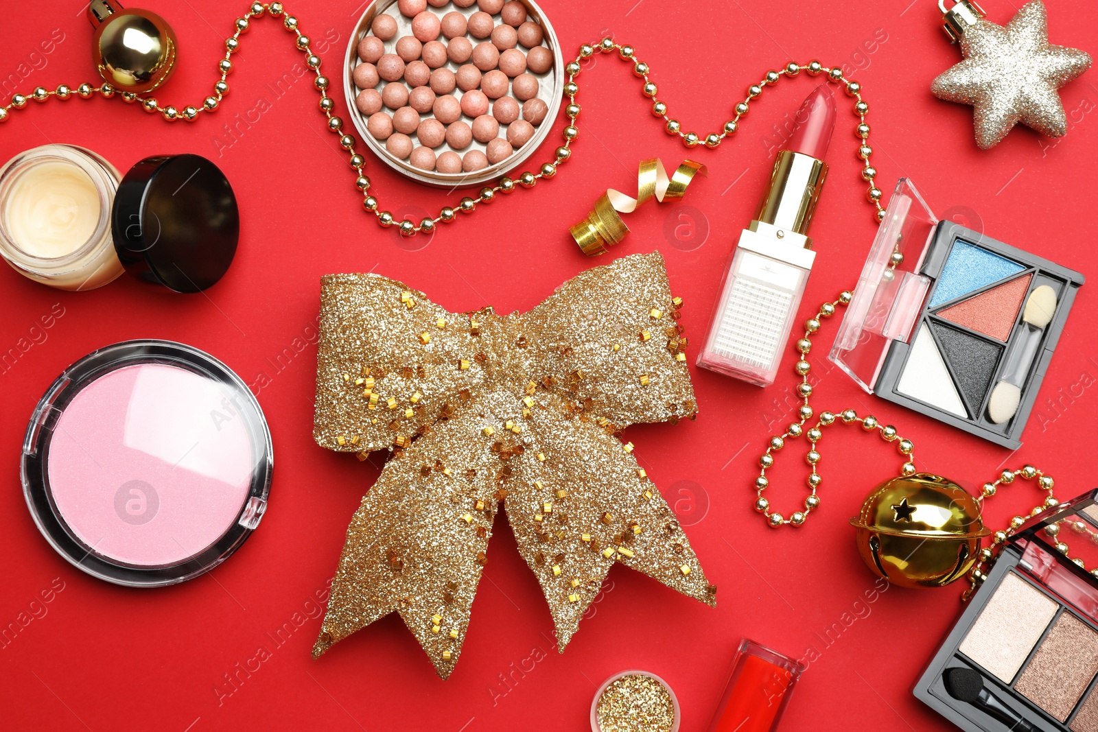 Photo of Flat lay composition with makeup products and Christmas decor on red background