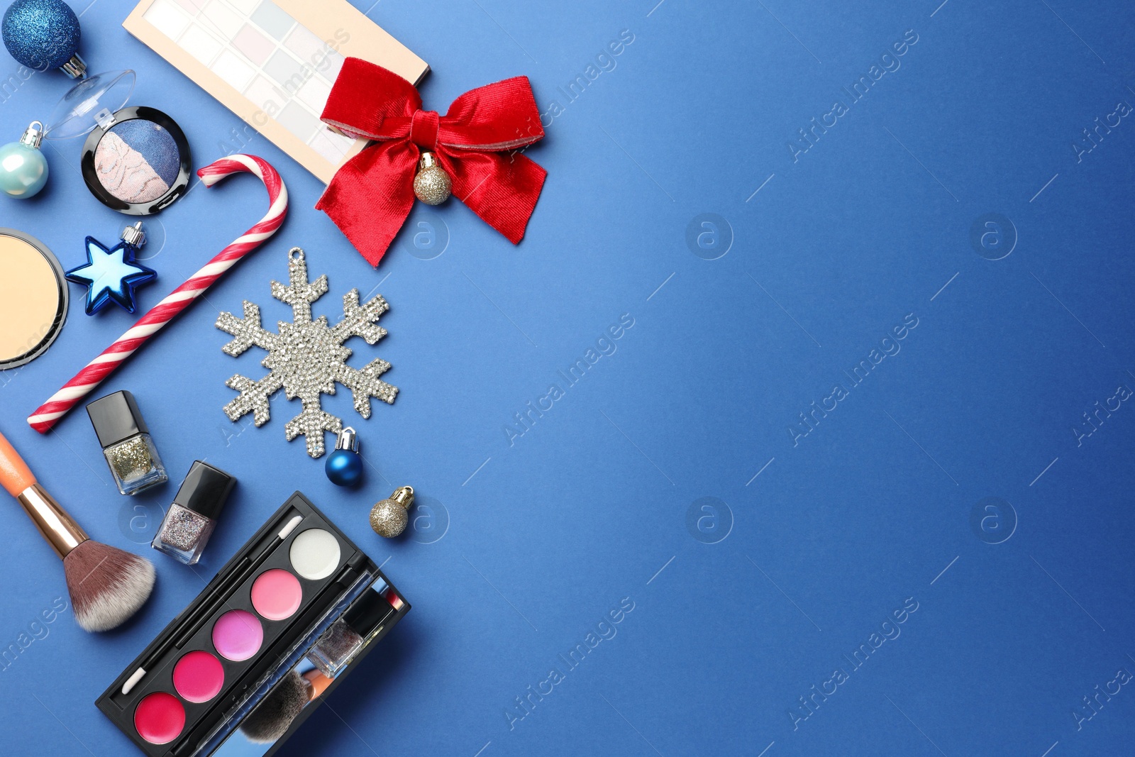 Photo of Flat lay composition with makeup products and Christmas decor on blue background. Space for text