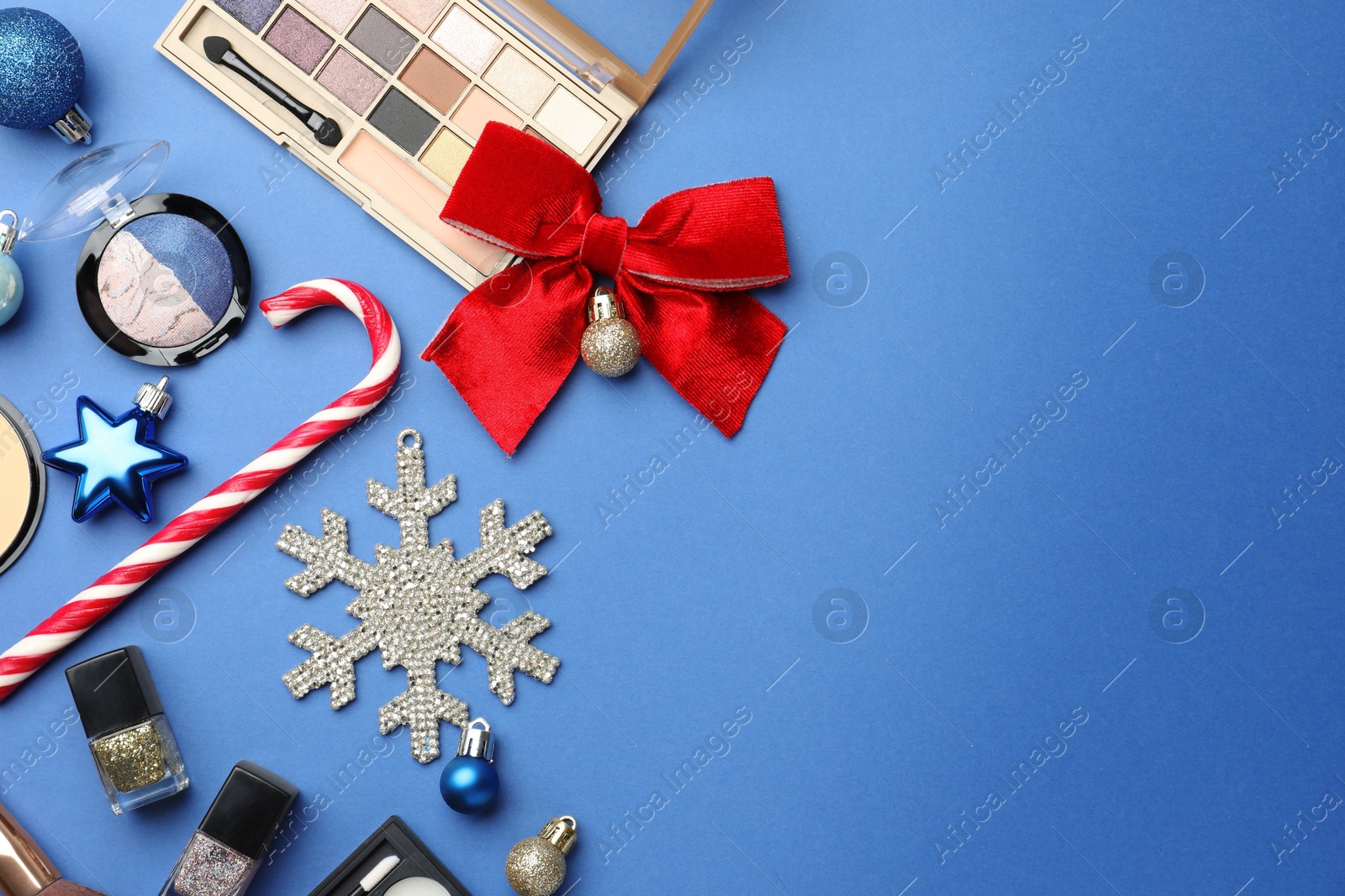 Photo of Flat lay composition with makeup products and Christmas decor on blue background. Space for text