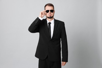 Photo of Young bodyguard in suit and sunglasses on grey background