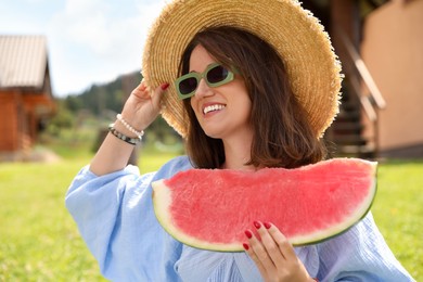 Happy woman with slice of juicy watermelon outdoors