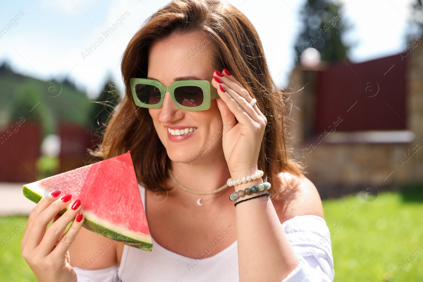 Photo of Happy woman holding slice of juicy watermelon outdoors