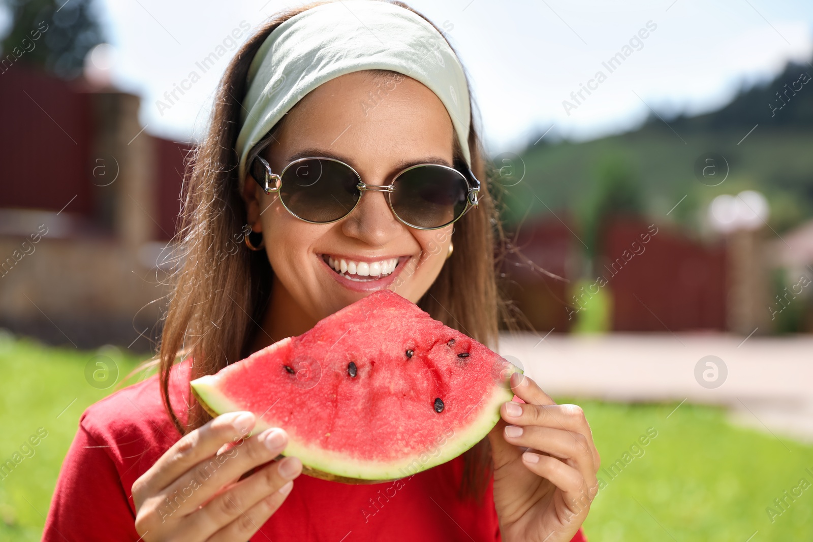 Photo of Happy woman in sunglasses eating juicy watermelon outdoors