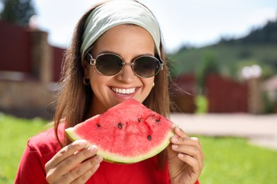 Photo of Happy woman in sunglasses eating juicy watermelon outdoors