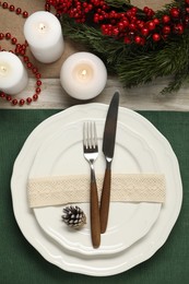 Photo of Christmas place setting with plates, cutlery and festive decor on wooden table, flat lay