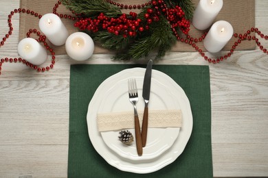 Photo of Christmas place setting with plates, cutlery and festive decor on wooden table, flat lay