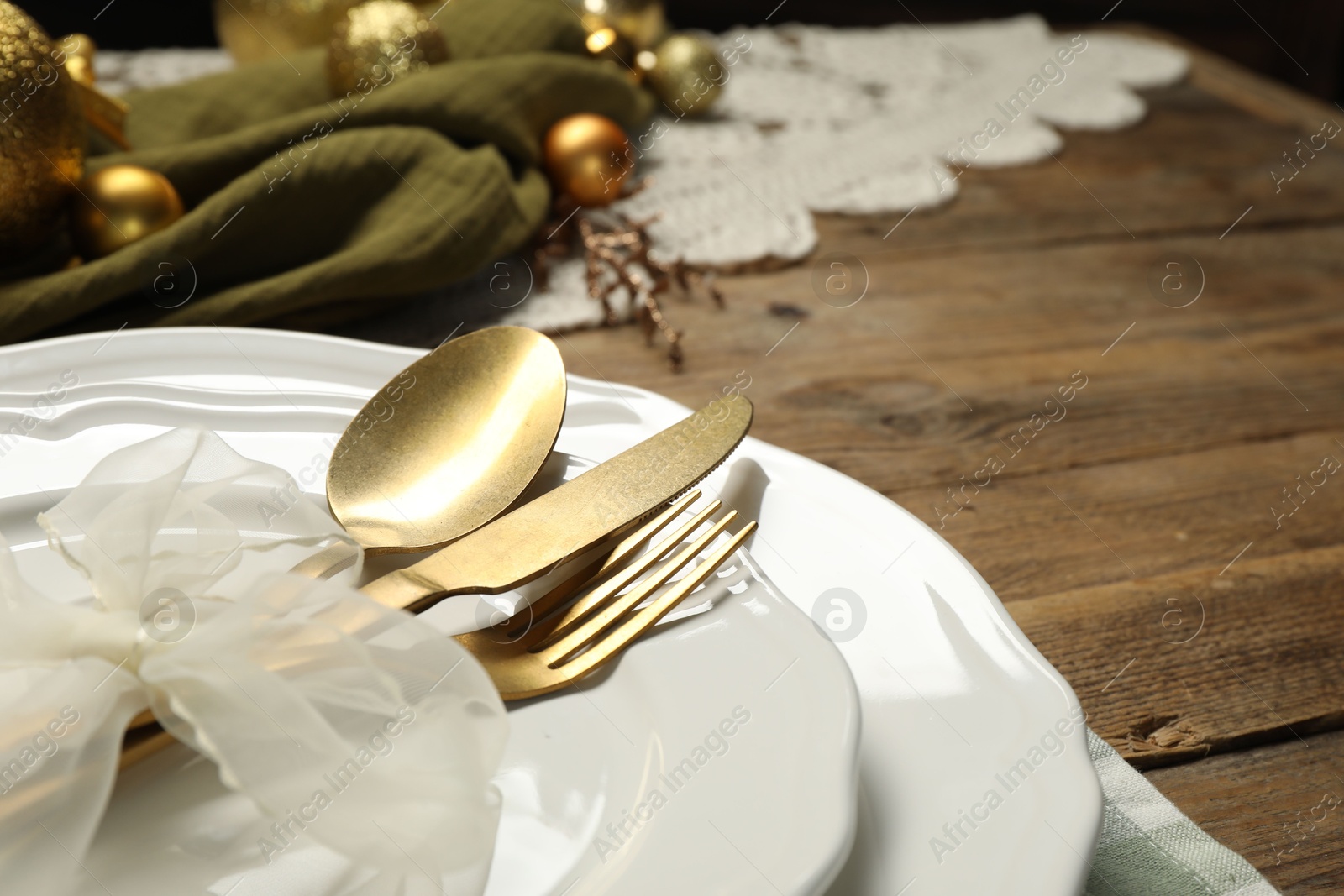 Photo of Plates, cutlery and Christmas decor on wooden table, closeup