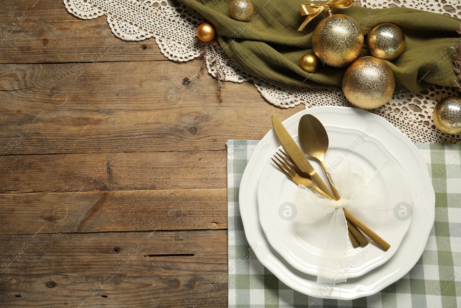 Photo of Christmas place setting with plates, cutlery and festive decor on wooden table, flat lay. Space for text