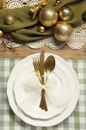 Photo of Christmas place setting with plates, cutlery and festive decor on wooden table, flat lay