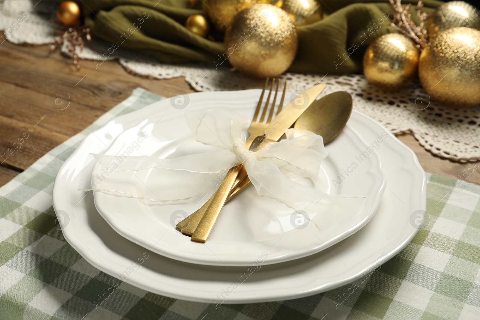 Photo of Plates, cutlery and Christmas decor on wooden table, closeup