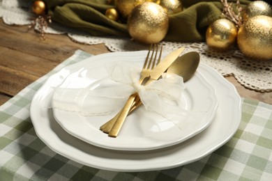 Photo of Plates, cutlery and Christmas decor on wooden table, closeup