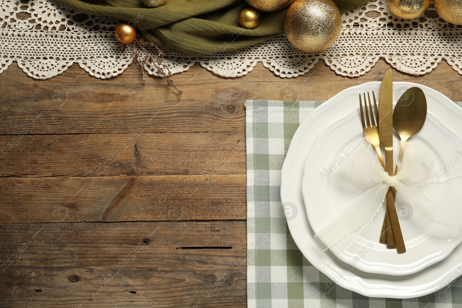 Photo of Christmas place setting with plates, cutlery and festive decor on wooden table, flat lay. Space for text