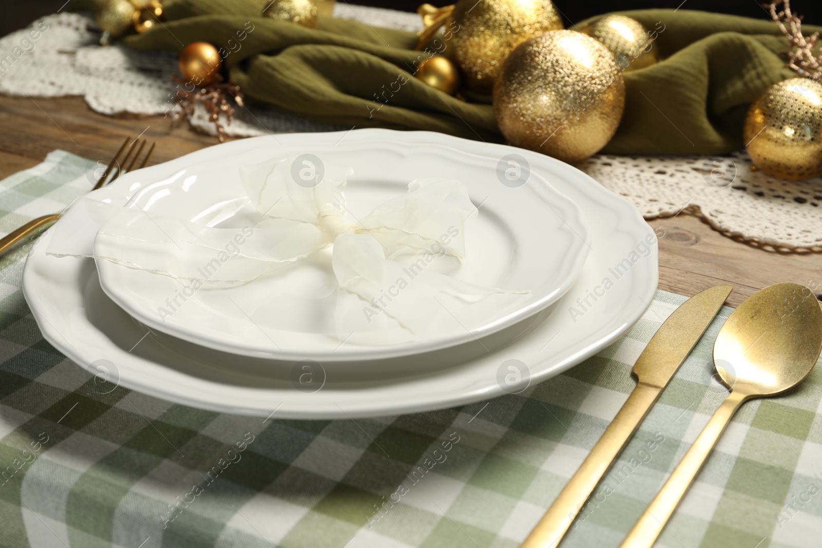 Photo of Plates, cutlery and Christmas decor on wooden table, closeup