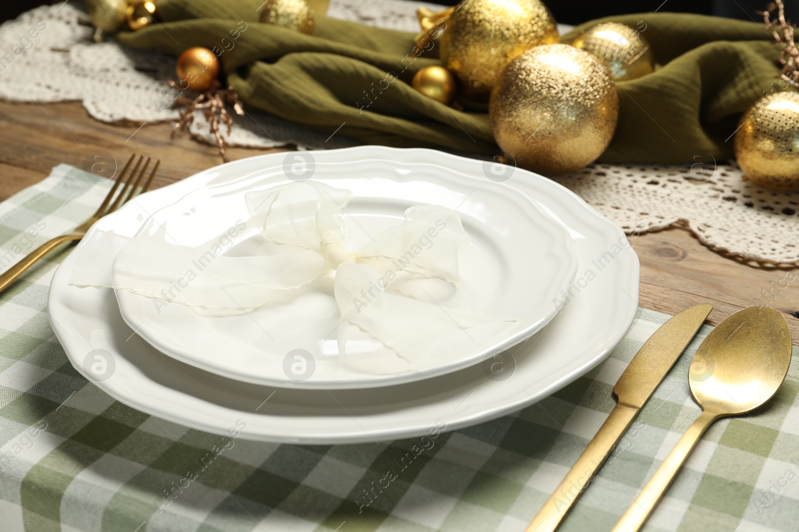 Photo of Plates, cutlery and Christmas decor on wooden table, closeup