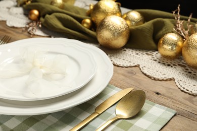 Photo of Plates, cutlery and Christmas decor on wooden table, closeup