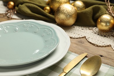 Photo of Plates, cutlery and Christmas decor on wooden table, closeup