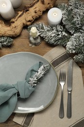 Photo of Christmas place setting with plate, cutlery and festive decor on wooden table, flat lay